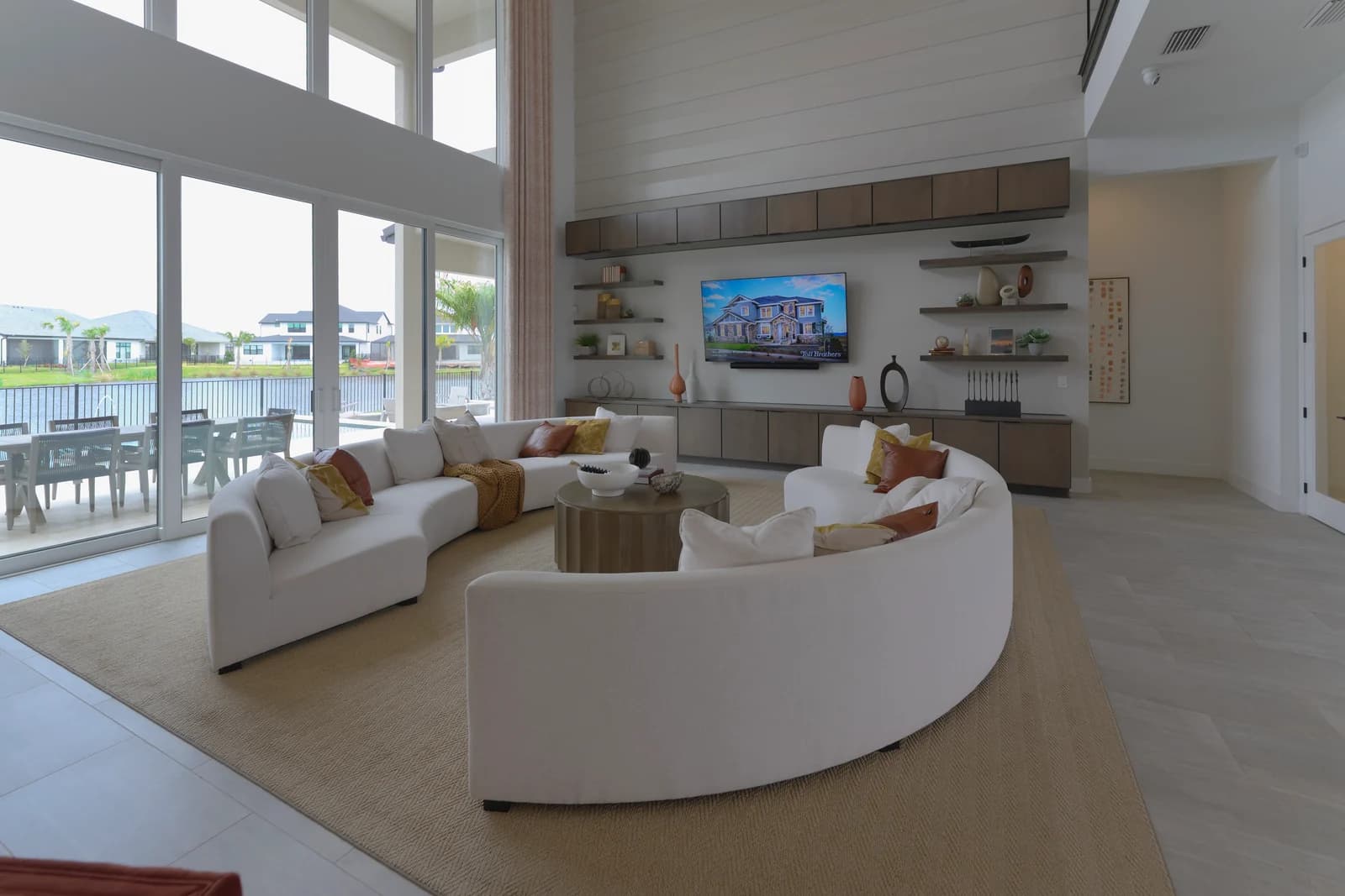 Great room in a Lake Nona home with a curved white sectional, built-in shelving, and sliding doors to a lakefront patio