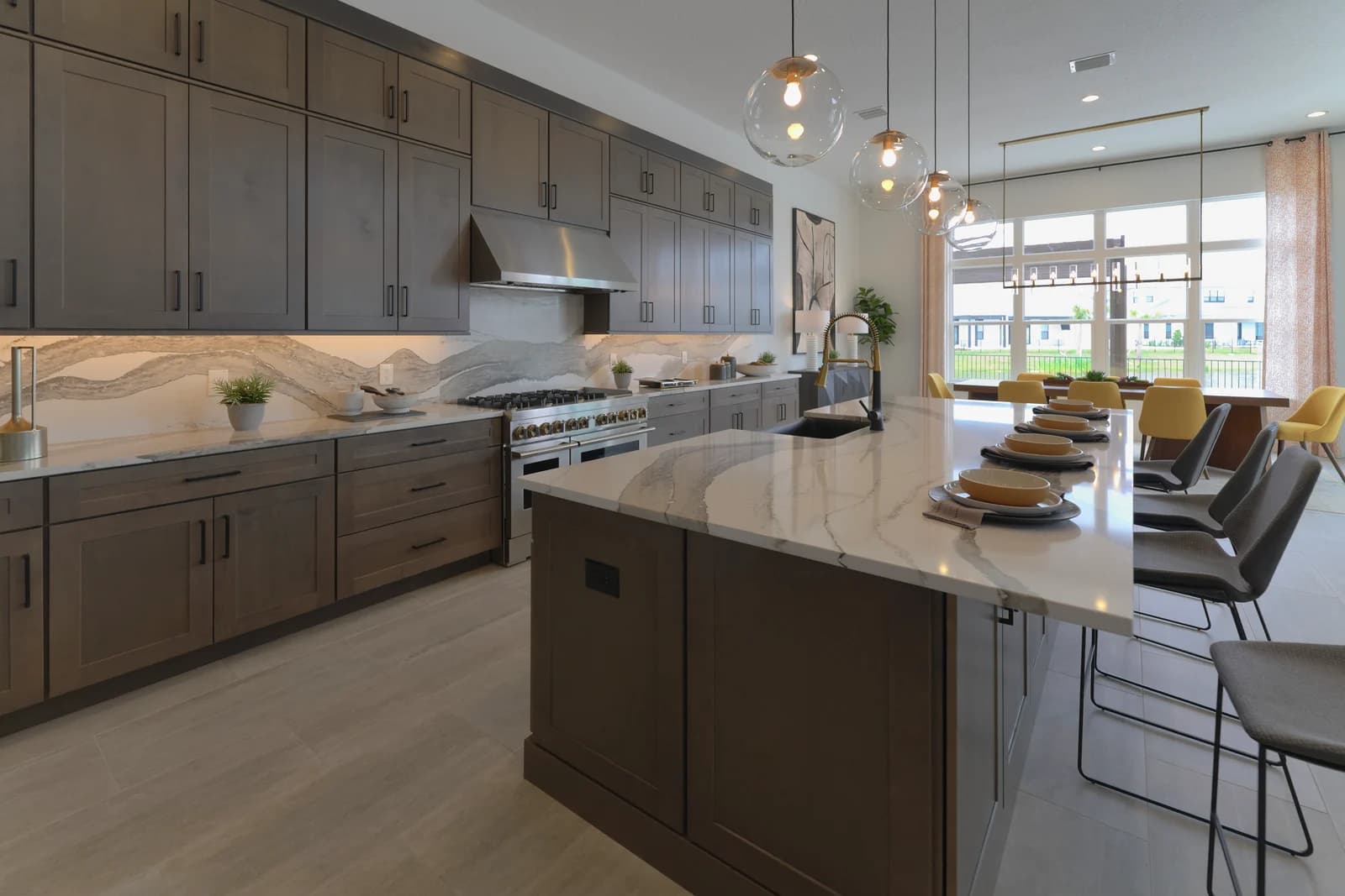 Veined quartz kitchen island set for four, with the dining area and lake view behind it