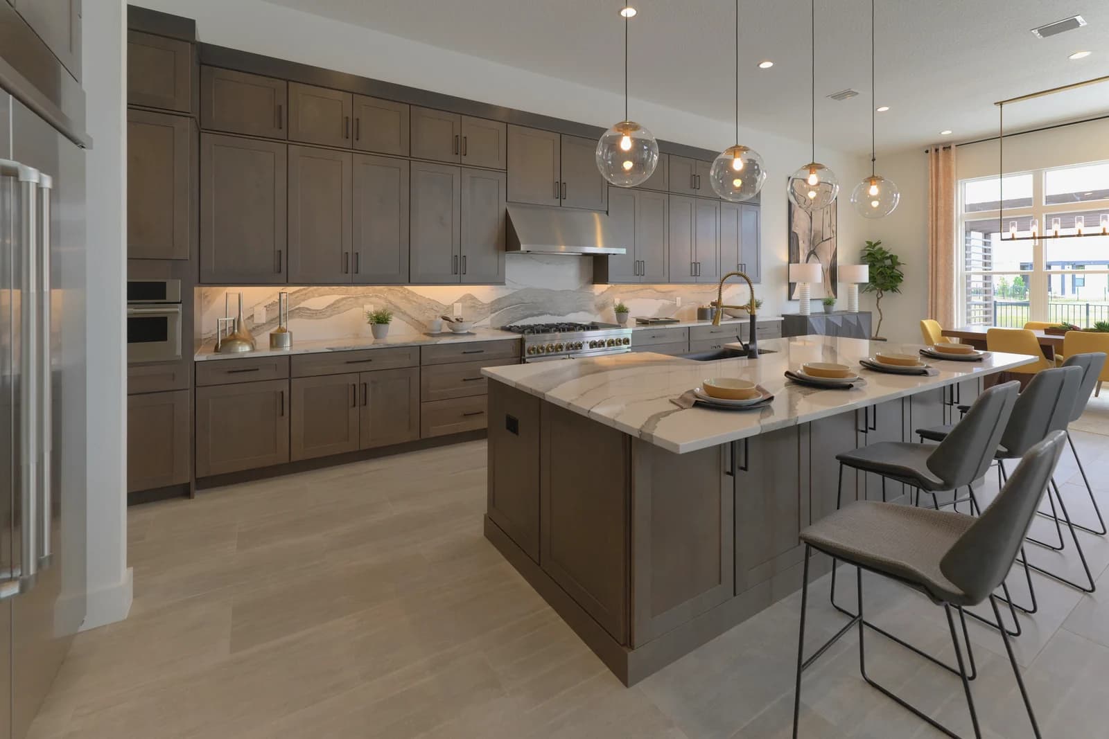 Real estate photography of a designer kitchen in Lake Nona with a quartz island, globe pendants, and a sunlit dining area