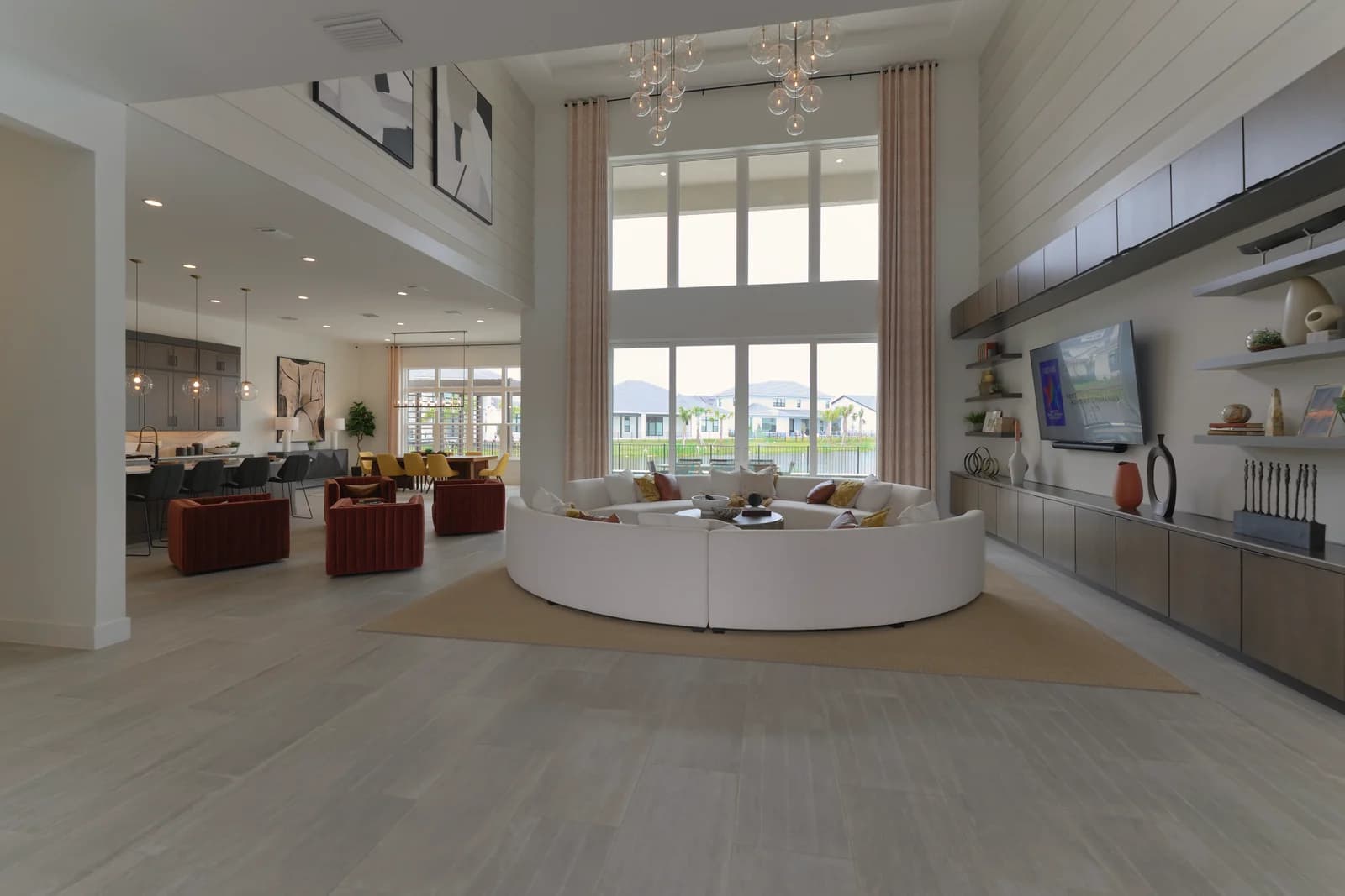 Two-story great room with floor-to-ceiling windows, full-height drapes, and a glass chandelier