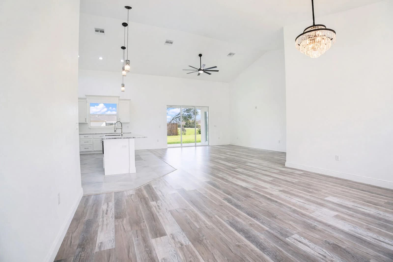 Bright open-plan living room and kitchen with vaulted ceilings and wood-look floors